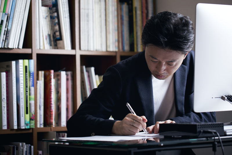 Japanese man writing a paper on desk at home office.